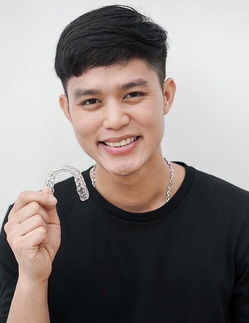 Man smiling while holding invisalign