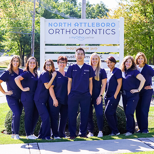 North Attleboro Orthodontics Team Smiling next to sign
