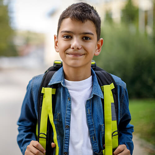Kid with backpack smiling outdoors
