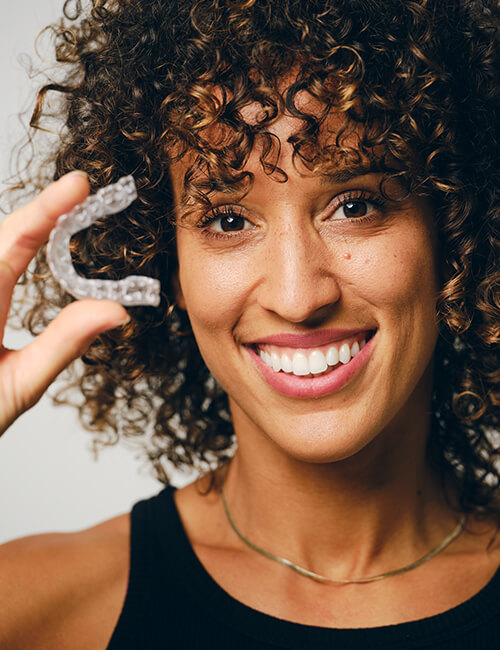 Woman with curly hair holding Invisalign on her hands
